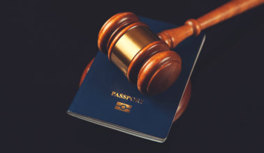 A judge's gavel positioned on a passport, illustrating the relationship between justice and global mobility.