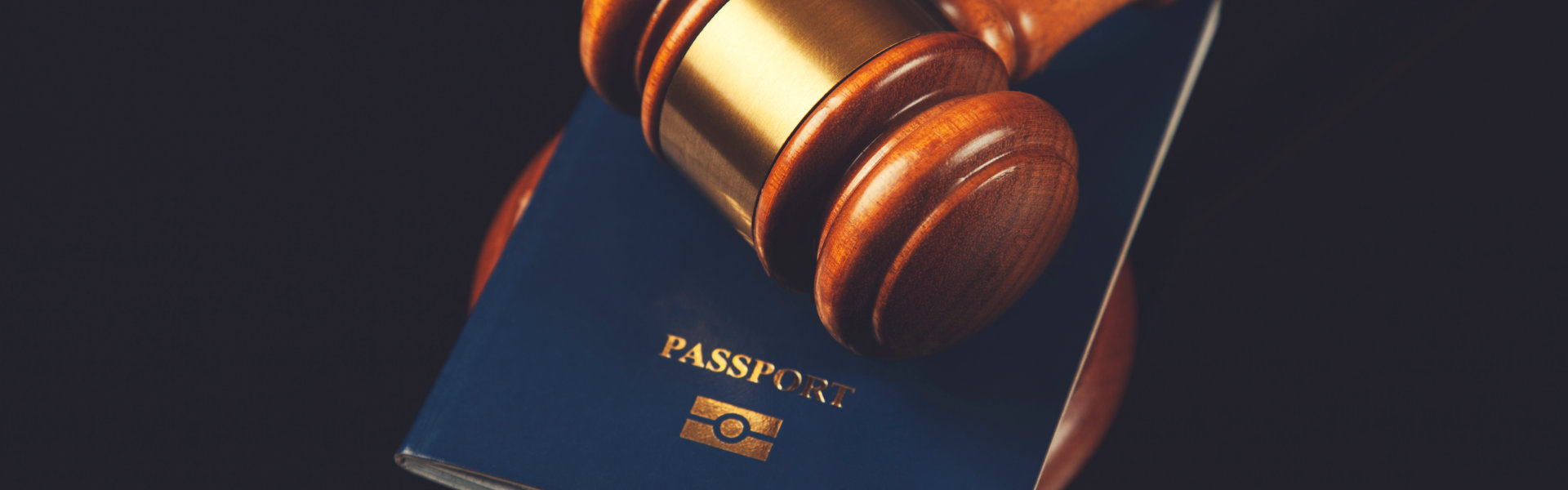 A judge's gavel positioned on a passport, illustrating the relationship between justice and global mobility.